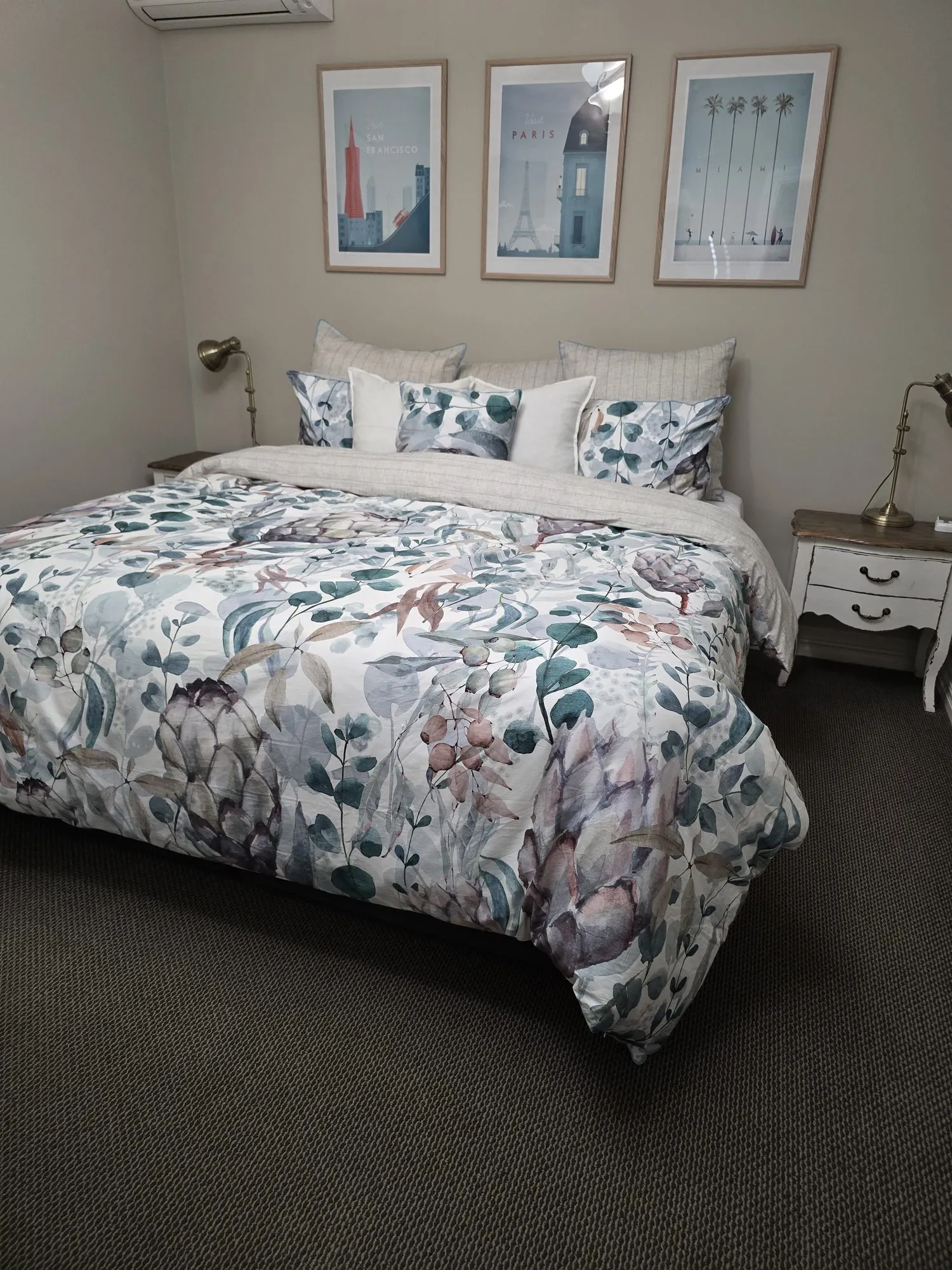Henry Charles main bedroom with a eucalyptus-print quilt beneath three framed Paris prints